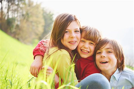 pre teen girl sit - Sister and younger brothers sitting in grassy field Stock Photo - Premium Royalty-Free, Code: 649-07520758