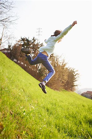 simsearch:649-07596731,k - Young boy jumping down steep grassy field Stock Photo - Premium Royalty-Free, Code: 649-07520763
