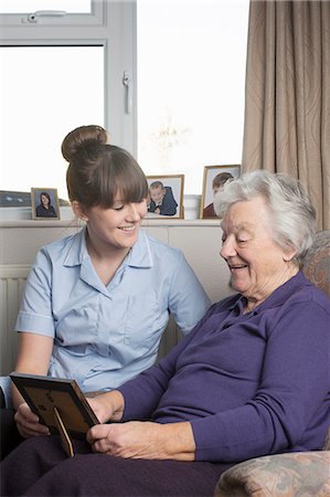 Personal care assistant looking at photograph with senior woman Stock Photo - Premium Royalty-Free, Code: 649-07521167