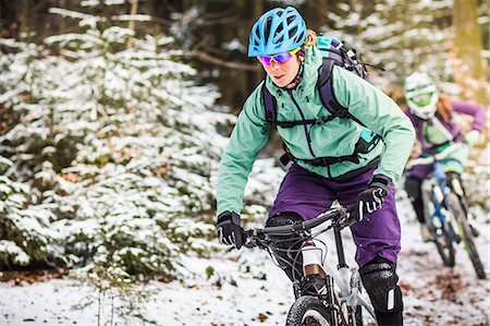 Two female mountain bikers riding through forest in snow Stock Photo - Premium Royalty-Free, Code: 649-07560125