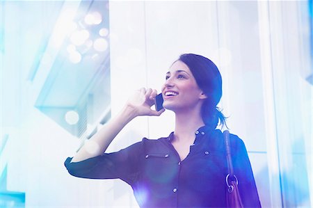 Young businesswoman talking on smartphone with lights coming out of it Stock Photo - Premium Royalty-Free, Code: 649-07560135