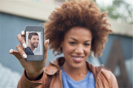 Young woman holding up smartphone with photograph of boyfriend Foto de stock - Sin royalties Premium, Código: 649-07560152