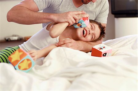 family arms around each other - Father and young son playing with building blocks on bed Stock Photo - Premium Royalty-Free, Code: 649-07585459