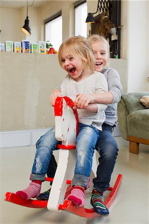 edad escolar primaria - Two young sisters playing on rocking horse Foto de stock - Sin royalties Premium, Código: 649-07585476