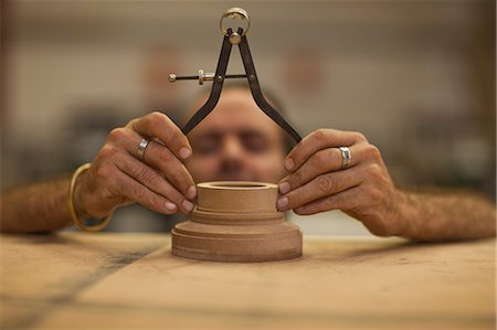 Close up of carpenter measuring turning wood in workshop Stock Photo - Premium Royalty-Free, Code: 649-07596225