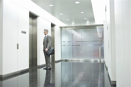 suit man eyeglasses - Businessman waiting for elevator in office corridor Stock Photo - Premium Royalty-Free, Code: 649-07596248