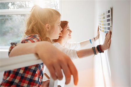 Teenage sisters holding color swatch against wall Stock Photo - Premium Royalty-Free, Code: 649-07596477