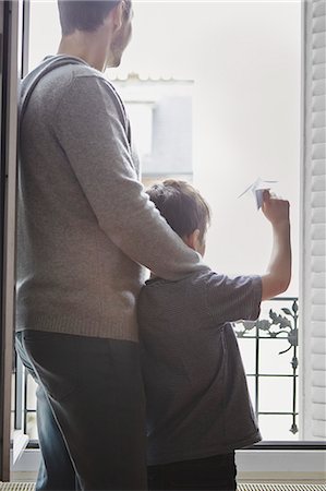 dad not mom child back - Boy launching paper plane from window Stock Photo - Premium Royalty-Free, Code: 649-07648115