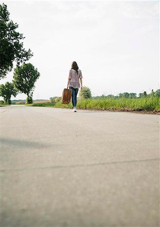 simsearch:649-08086253,k - Young woman walking on country road carrying suitcase Stock Photo - Premium Royalty-Free, Code: 649-07648344