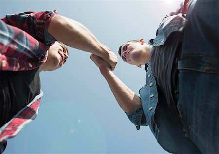 View from below of young men, shaking hands Stock Photo - Premium Royalty-Free, Code: 649-07710452