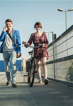 Young couple pushing bicycle over bridge Stock Photo - Premium Royalty-Free, Code: 649-07736961