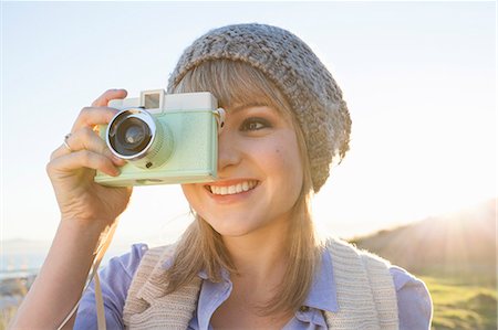 smiling portrait looking away - Young woman taking photograph with camera at sunset Photographie de stock - Premium Libres de Droits, Code: 649-07737010
