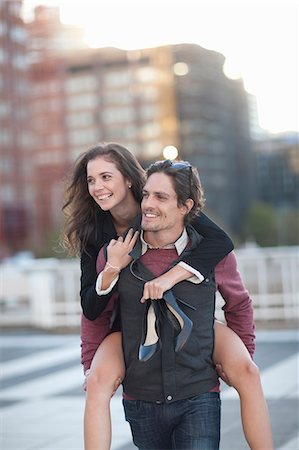 divertimento - Mid adult man giving girlfriend piggyback in street Fotografie stock - Premium Royalty-Free, Codice: 649-07737040