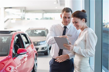 Salesman and female customer using digital tablet in car dealership Photographie de stock - Premium Libres de Droits, Code: 649-07761178