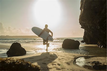 Mature man running towards sea, holding surf board Stock Photo - Premium Royalty-Free, Code: 649-07804065