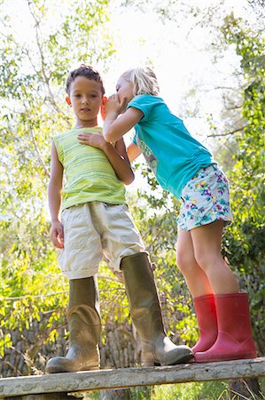 simsearch:649-07804176,k - Girl whispering to boy whilst standing on garden bench Stock Photo - Premium Royalty-Free, Code: 649-07804157