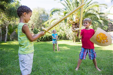 simsearch:649-07804176,k - Three children in garden playing with toy swords Stock Photo - Premium Royalty-Free, Code: 649-07804153