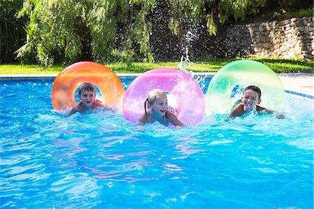simsearch:649-07804176,k - Three children racing on inflatable rings in garden swimming pool Stock Photo - Premium Royalty-Free, Code: 649-07804165