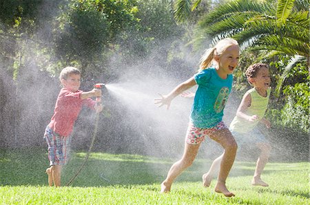simsearch:649-08180244,k - Three children in garden chasing each other with water sprinkler Stock Photo - Premium Royalty-Free, Code: 649-07804177