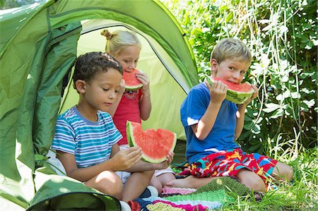 simsearch:649-07804176,k - Three children eating watermelon slices in garden tent Stock Photo - Premium Royalty-Free, Code: 649-07804171