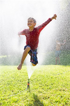 simsearch:649-07804176,k - Boy jumping over water sprinkler in garden Stock Photo - Premium Royalty-Free, Code: 649-07804180