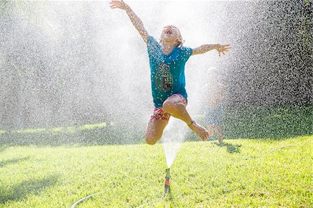 simsearch:649-07804176,k - Girl jumping over water sprinkler in garden Stock Photo - Premium Royalty-Free, Code: 649-07804181