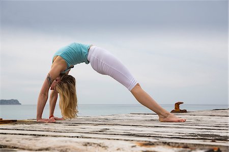 simsearch:614-06168927,k - Mid adult woman bending over backwards practicing yoga on wooden sea pier Stock Photo - Premium Royalty-Free, Code: 649-07804688