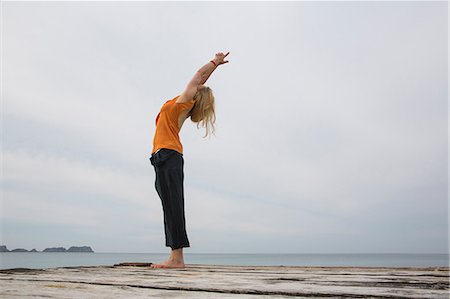simsearch:614-06168927,k - Mid adult woman stretching back practicing yoga on wooden sea pier Stock Photo - Premium Royalty-Free, Code: 649-07804690
