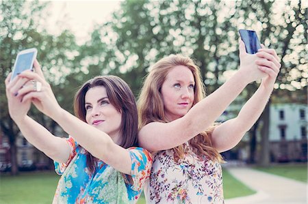 simsearch:649-07736862,k - Two young female friends taking selfie on smartphones side by side Stock Photo - Premium Royalty-Free, Code: 649-07804829