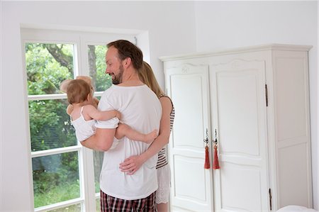 french door window - Father holding baby daughter, woman with arm around man Stock Photo - Premium Royalty-Free, Code: 649-07805143