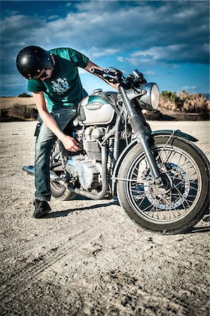 road bikers - Mid adult man checking motorcycle on arid plain, Cagliari, Sardinia, Italy Stock Photo - Premium Royalty-Free, Code: 649-07803245