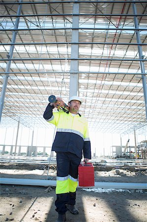 Surveyor carrying case and tripod on construction site Stock Photo - Premium Royalty-Free, Code: 649-07803340