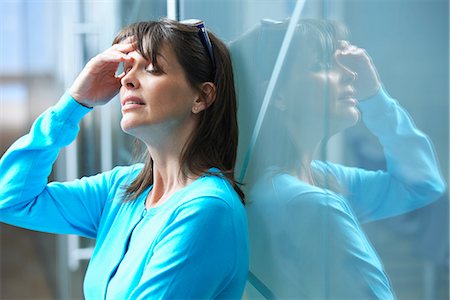 simsearch:649-07119200,k - Mature businesswoman leaning against glass wall in office with hand on face Stock Photo - Premium Royalty-Free, Code: 649-07803568