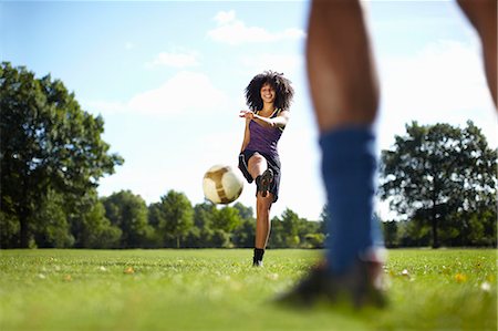fitness in park - Young woman kicking soccer ball toward boyfriend in park Stock Photo - Premium Royalty-Free, Code: 649-07803627