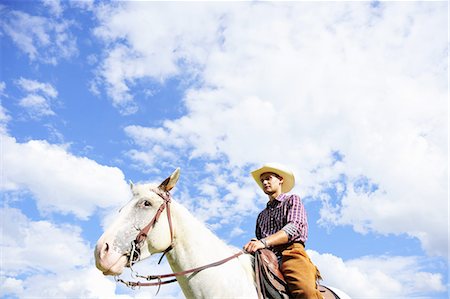 Low angle portrait of young man in cowboy gear riding  horse Photographie de stock - Premium Libres de Droits, Code: 649-07803712