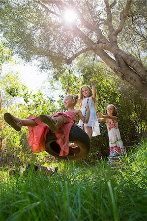 simsearch:649-07804176,k - Low angle view of three girls playing on tree tire swing in garden Stock Photo - Premium Royalty-Free, Code: 649-07803986