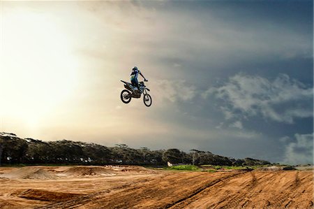 risk and control - Silhouetted young male motocross racer jumping mid air over mud track Stock Photo - Premium Royalty-Free, Code: 649-07905008