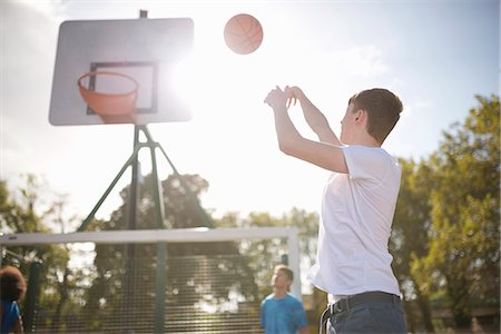 Young male basketball player throwing basketball into hoop Stock Photo - Premium Royalty-Free, Code: 649-07905680