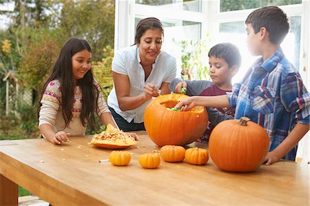 Mother and children carving pumpkin in dining room Stock Photo - Premium Royalty-Free, Code: 649-08004042