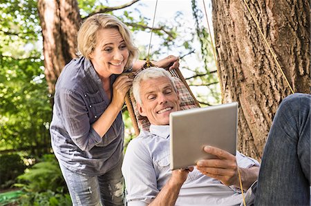 senior technology - Wife watching husband using digital tablet on hammock Stock Photo - Premium Royalty-Free, Code: 649-08004117