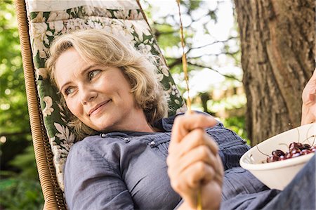 Mature woman relaxing with bowl of cherries on hammock Foto de stock - Sin royalties Premium, Código: 649-08004112