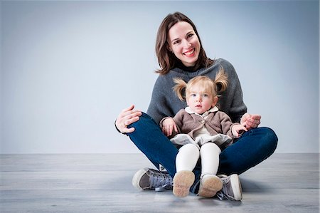 Portrait of mid adult woman sitting on floor with toddler daughter sitting on lap Stock Photo - Premium Royalty-Free, Code: 649-08003920