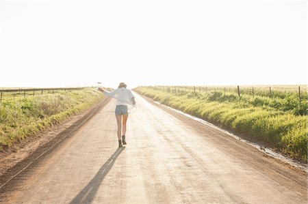 people walking in the distance - Mid adult woman walking down country road, rear view Stock Photo - Premium Royalty-Free, Code: 649-08003948