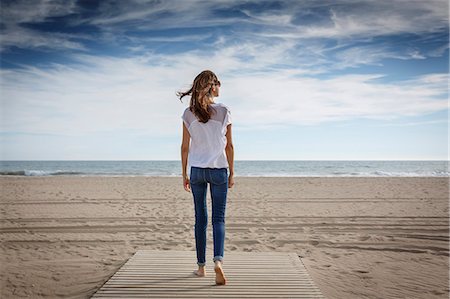 Rear view of mid adult woman strolling on beach, Castelldefels, Catalonia, Spain Stock Photo - Premium Royalty-Free, Code: 649-08060184