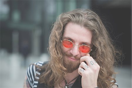 Portrait of young male hippy with orange sunglasses and tattooed fingers Stock Photo - Premium Royalty-Free, Code: 649-08060318