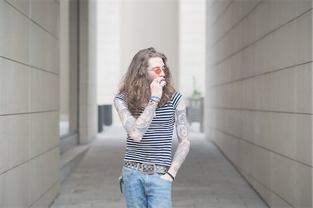 simsearch:877-06833898,k - Young male hippy smoking cigarette in city alley Stock Photo - Premium Royalty-Free, Code: 649-08060336