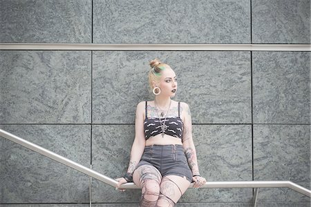 Portrait of young female tattooed punk sitting on subway railing Stock Photo - Premium Royalty-Free, Code: 649-08060333