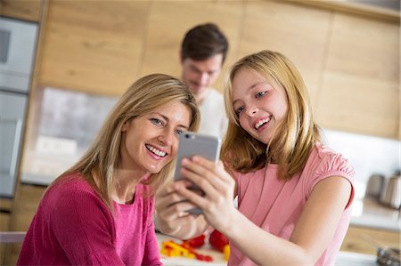 simsearch:649-07804673,k - Mid adult woman and daughter taking smartphone selfie in dining room Photographie de stock - Premium Libres de Droits, Code: 649-08060393