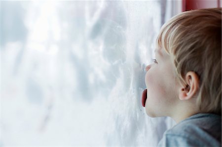 Boy licking inside of snow-covered window Stock Photo - Premium Royalty-Free, Code: 649-08060897