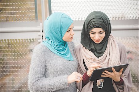 Two young women wearing hijabs using touchscreen on digital tablet on footbridge Photographie de stock - Premium Libres de Droits, Code: 649-08086836